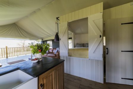 A view of the interior of the safari tent from the kitchen, showing the cabin bed