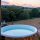 A wood-fired hot tub at sunset facing a wooded valley with the clouds a orangey red in the background