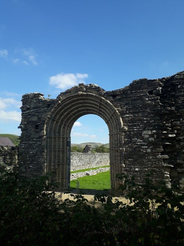 Strata Florida, an ancient stone arch, with the countryside beyon